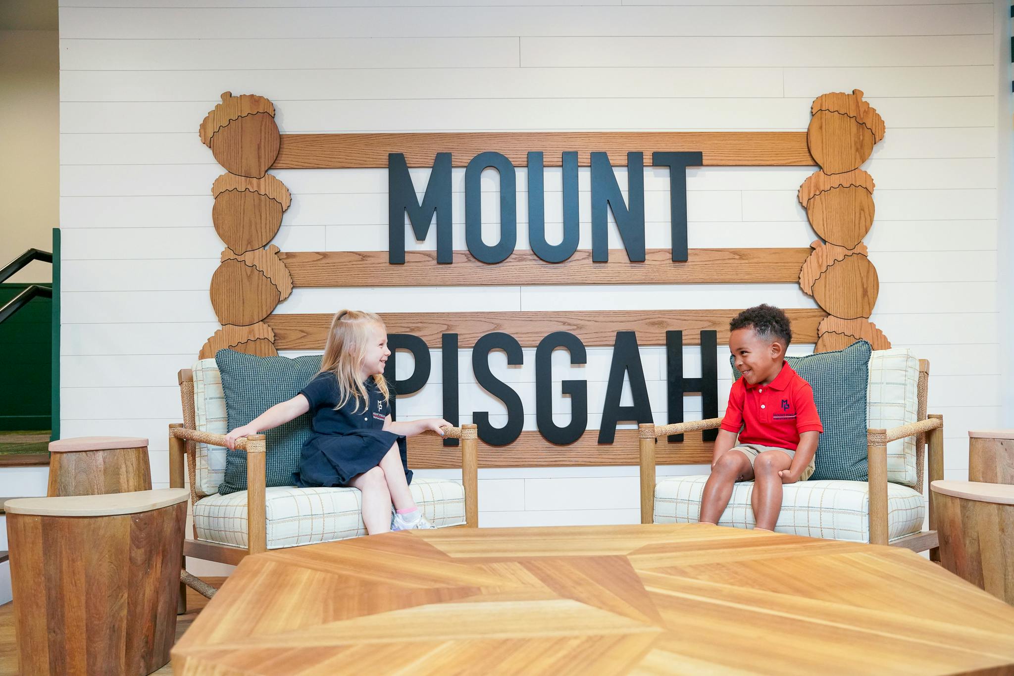 Two children sitting on a bench in front of a "MOUNT PISGAH" sign