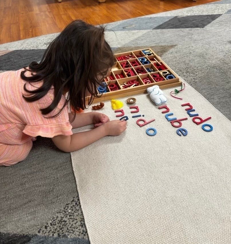 Child on floor arranging letter tiles to spell words