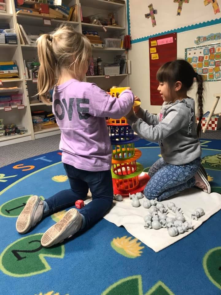 Two children playing with a colorful stacking toy on a rug