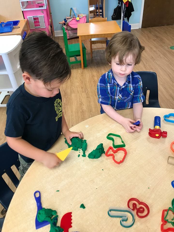 Two children playing with playdough at a table