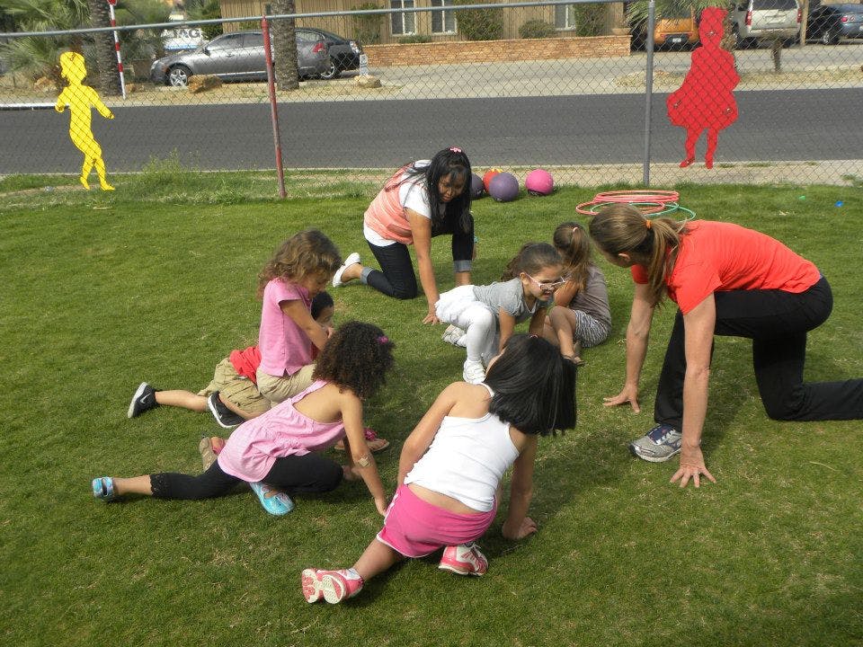 Adults and children on hands and knees on grass