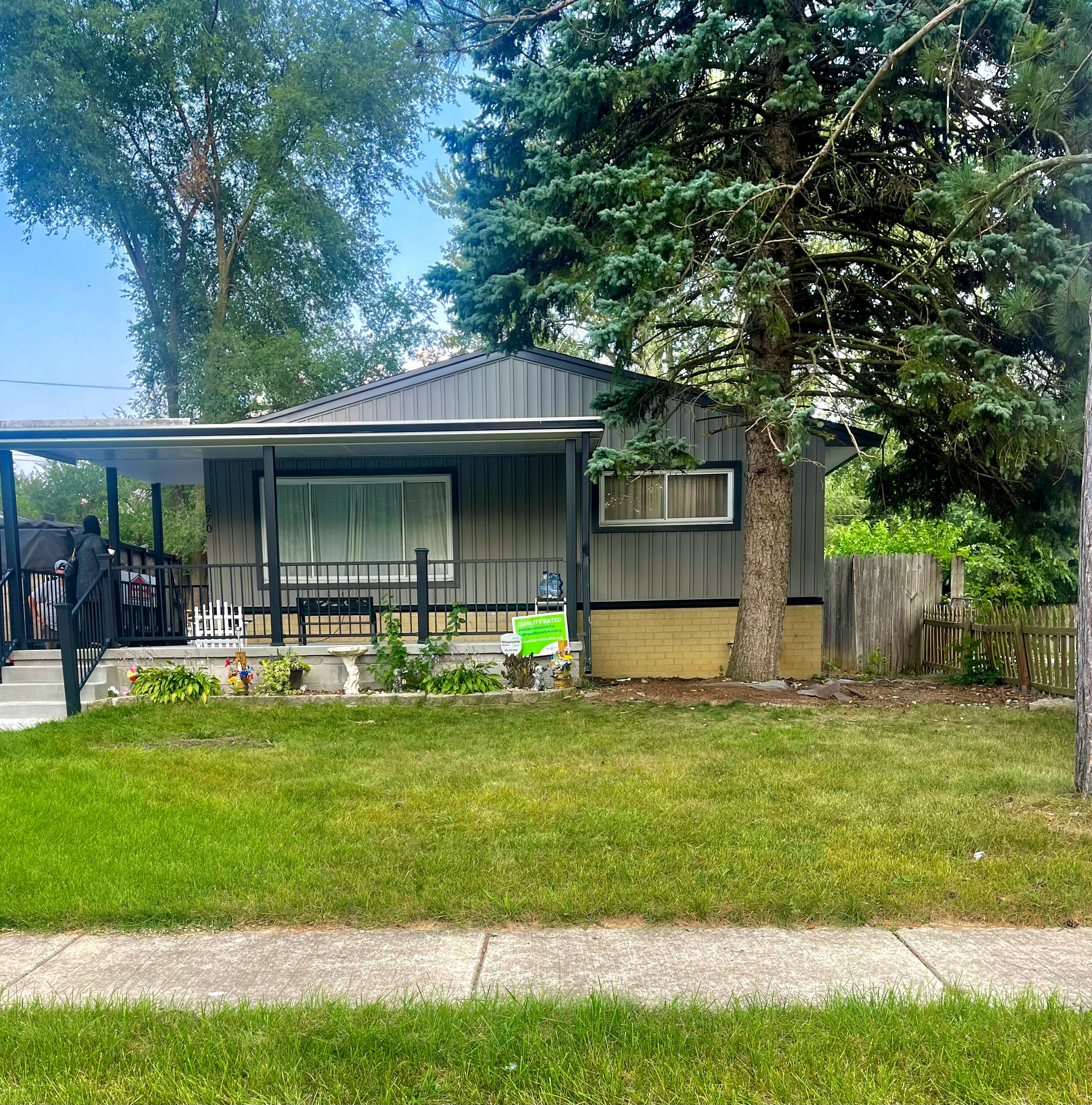 Small house with a covered porch and a large tree in front