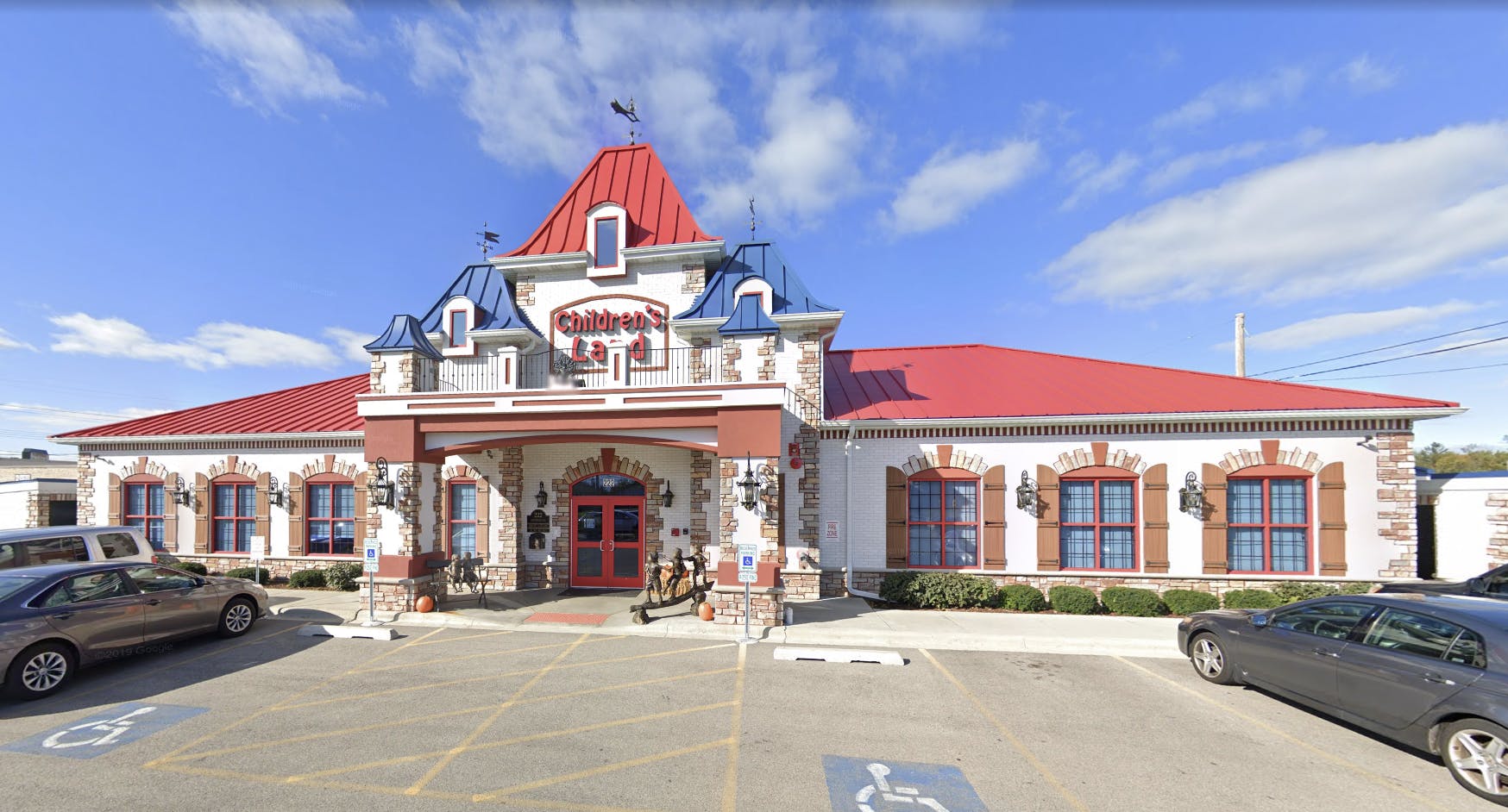 Building with red roof and blue accents, with cars in a parking lot