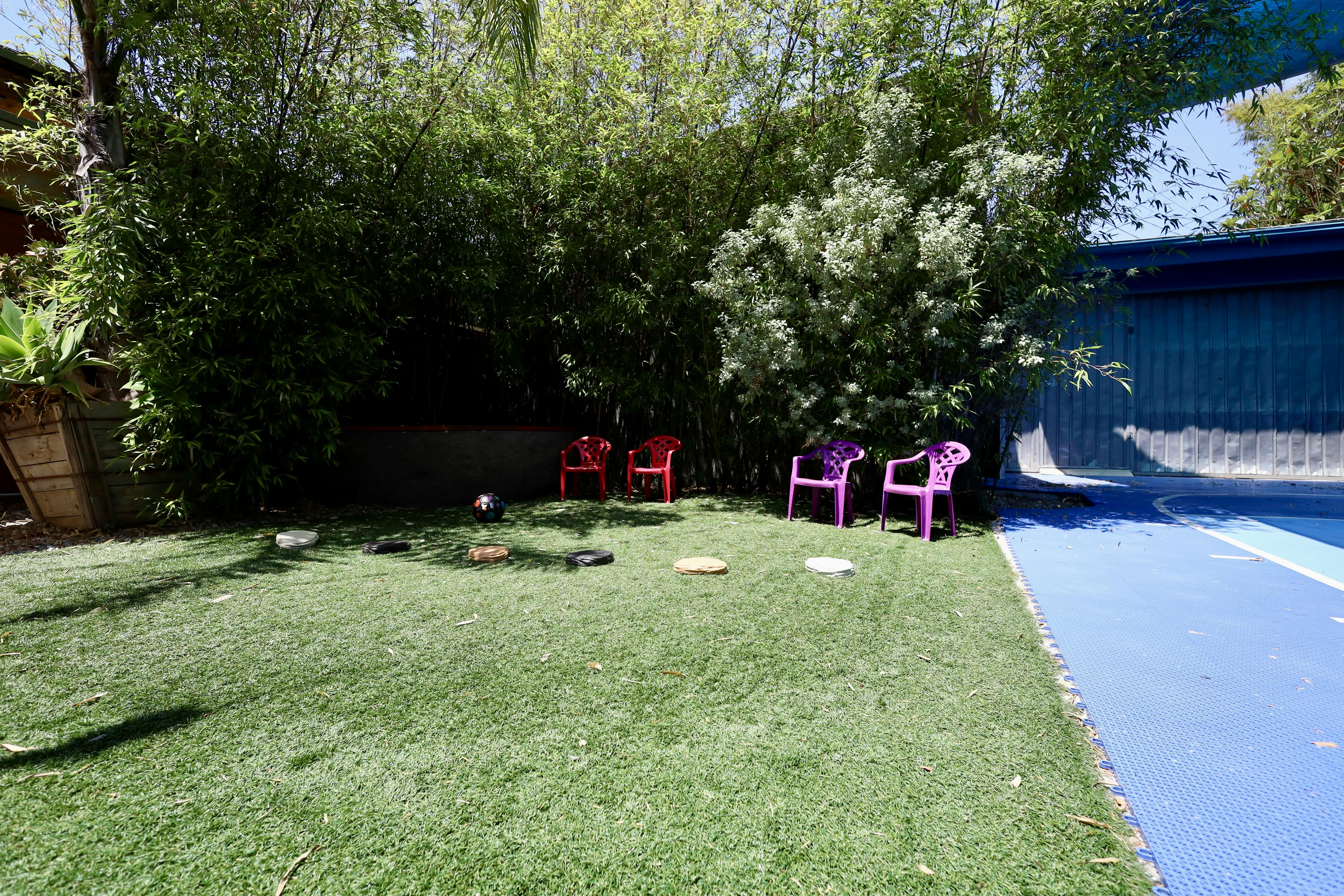 Faux grass area with red and purple chairs and a basketball