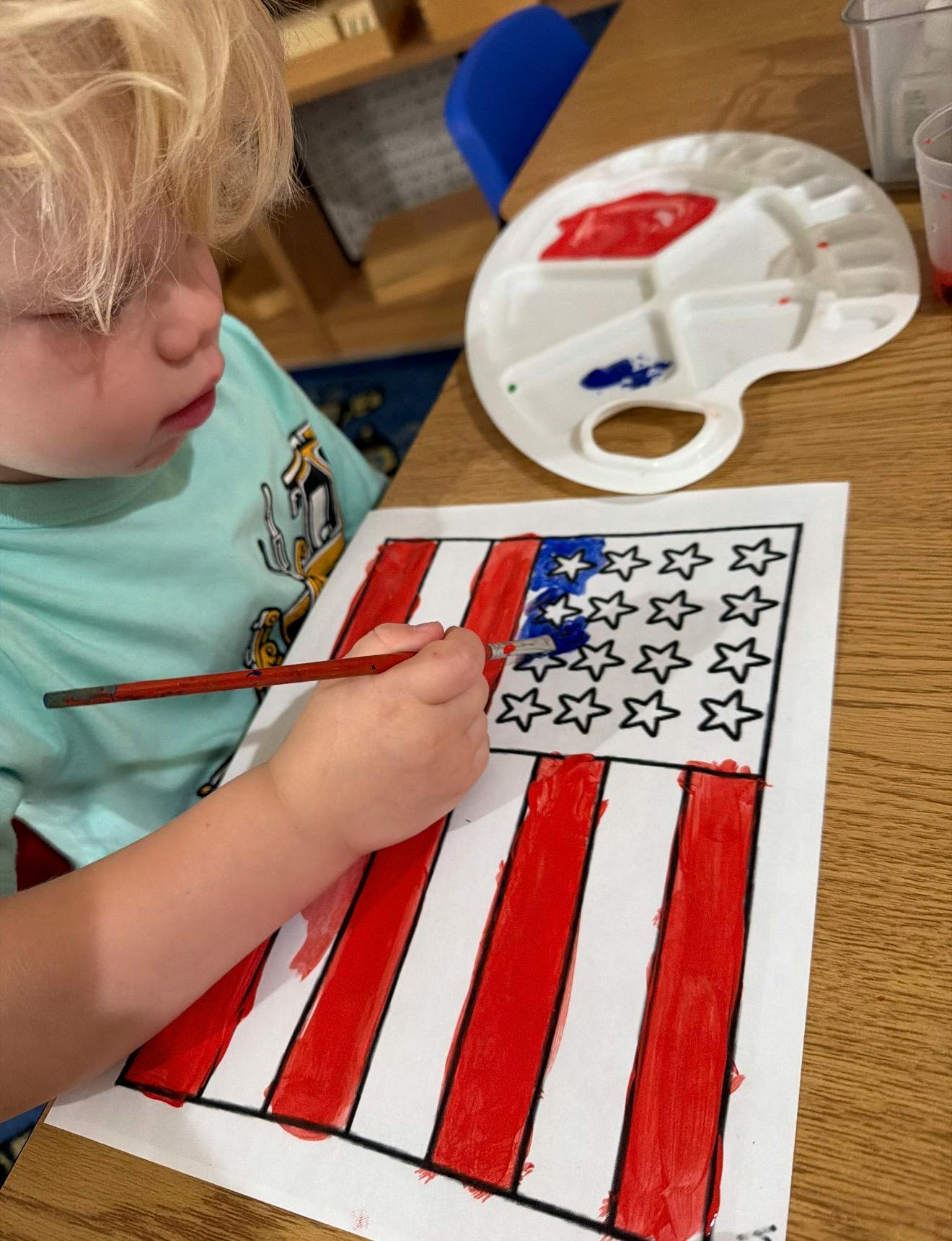 Child painting an American flag on paper