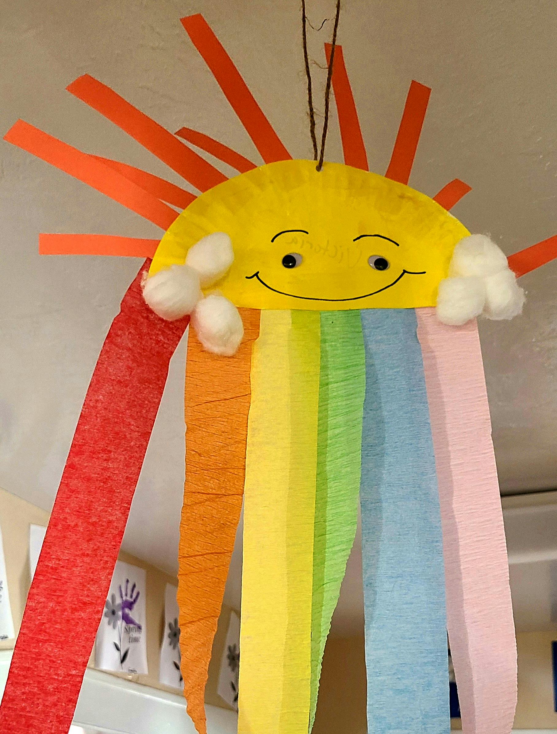 Paper plate sun craft with rainbow streamers and cotton ball clouds
