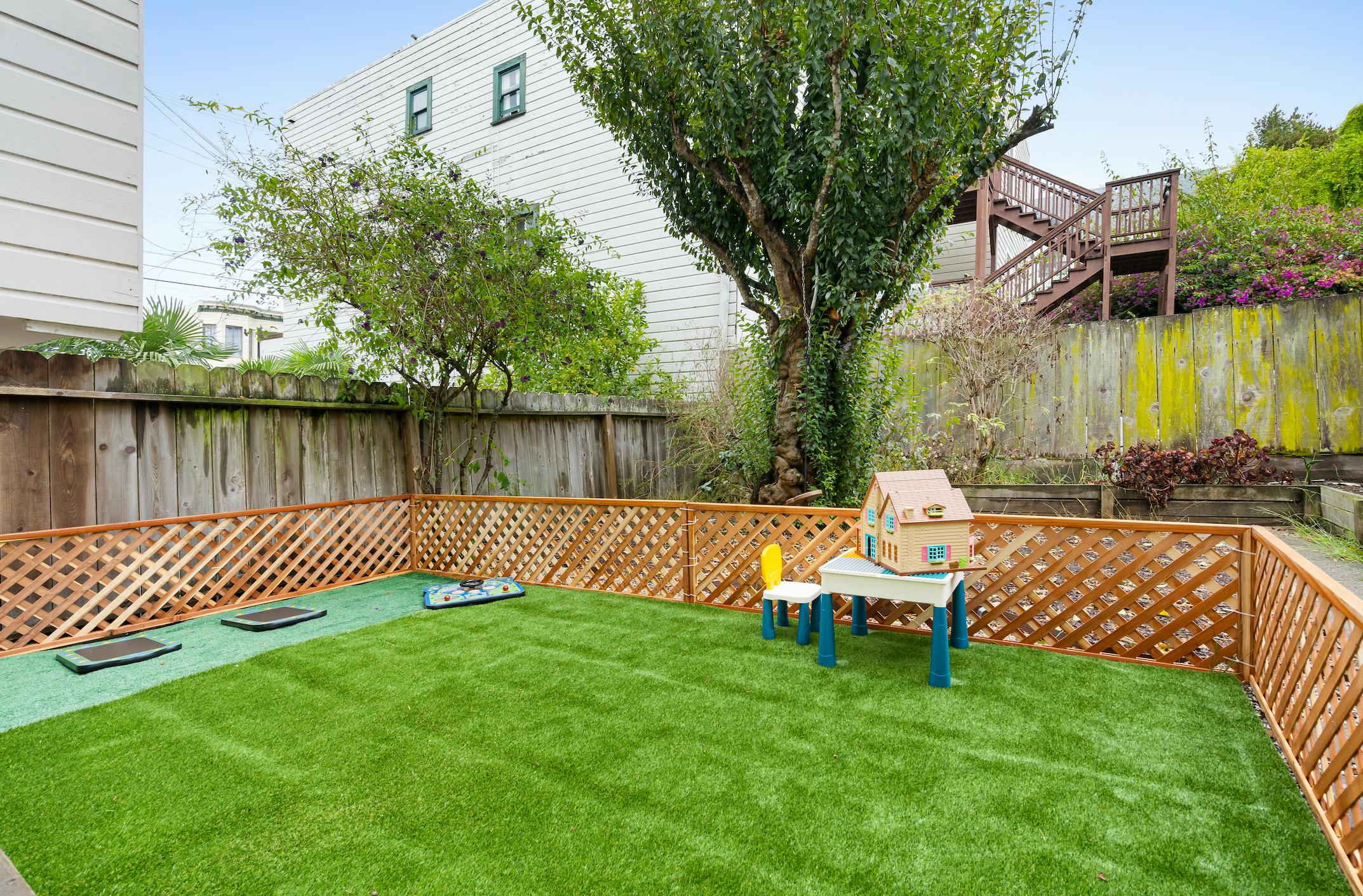 Fenced backyard with artificial grass and a small table and chair