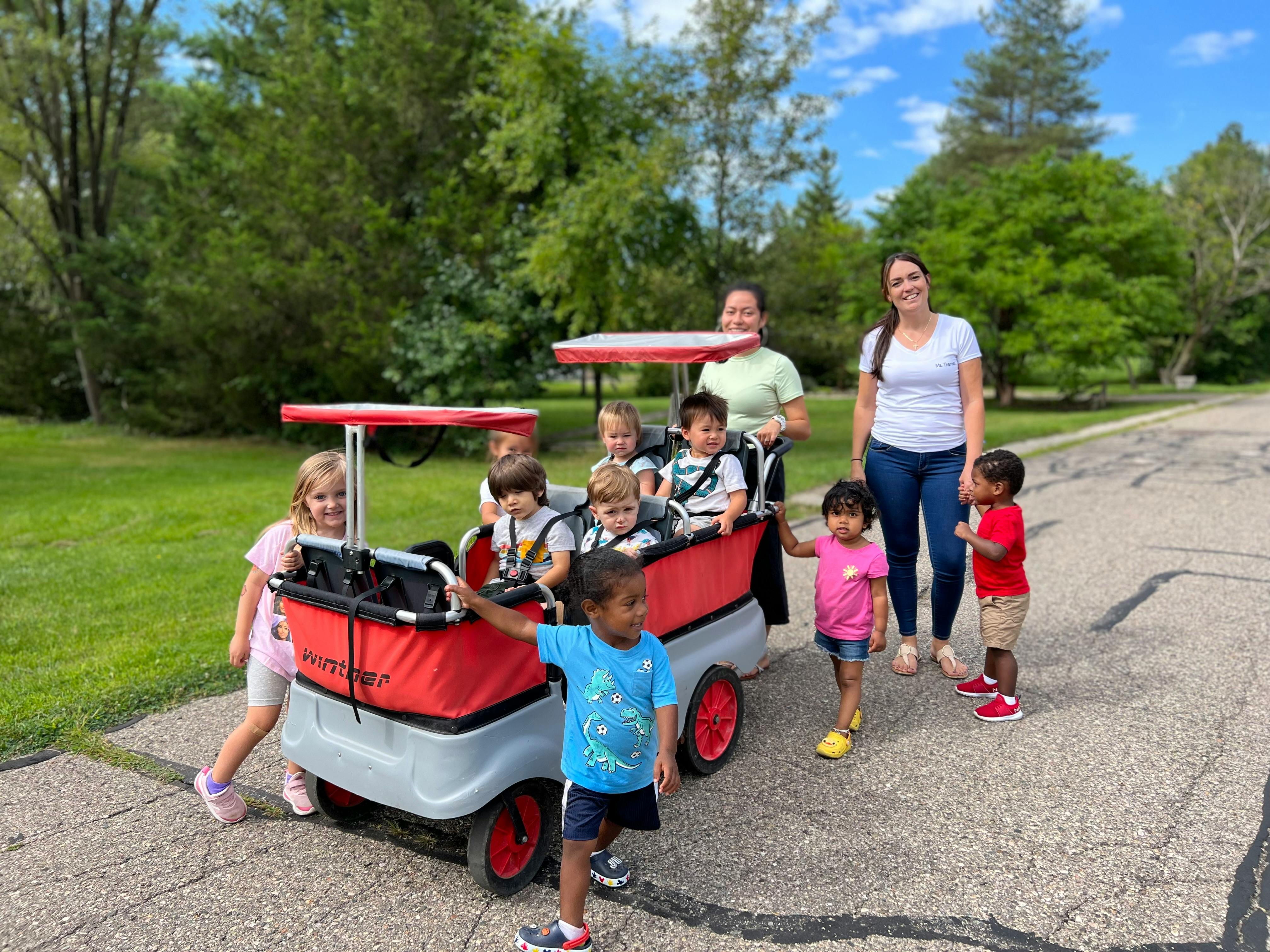 Two people with multiple children in and around a large wagon