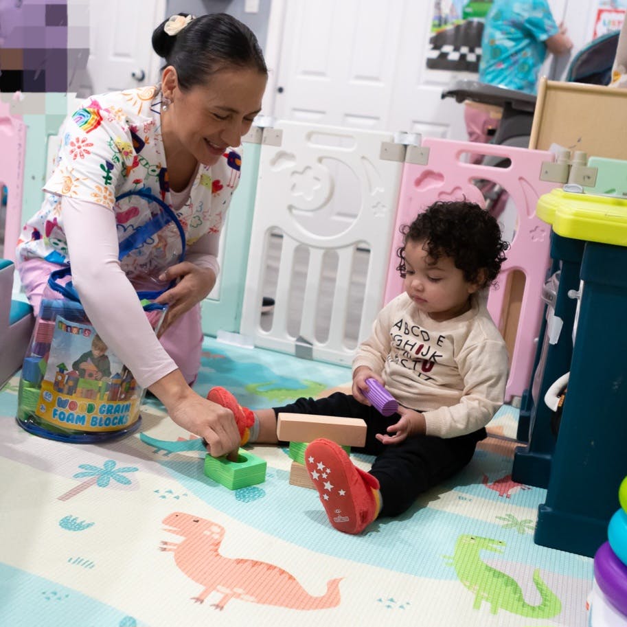 Adult and child playing with blocks on a mat
