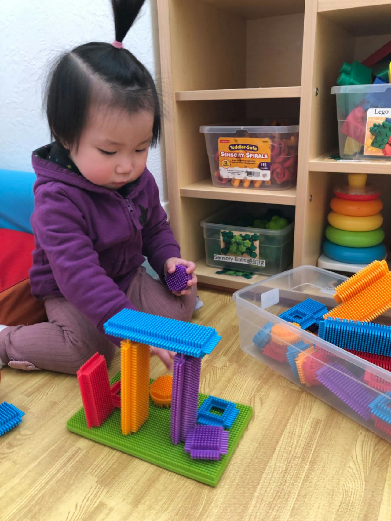 Child playing with colorful interlocking building blocks on the floor