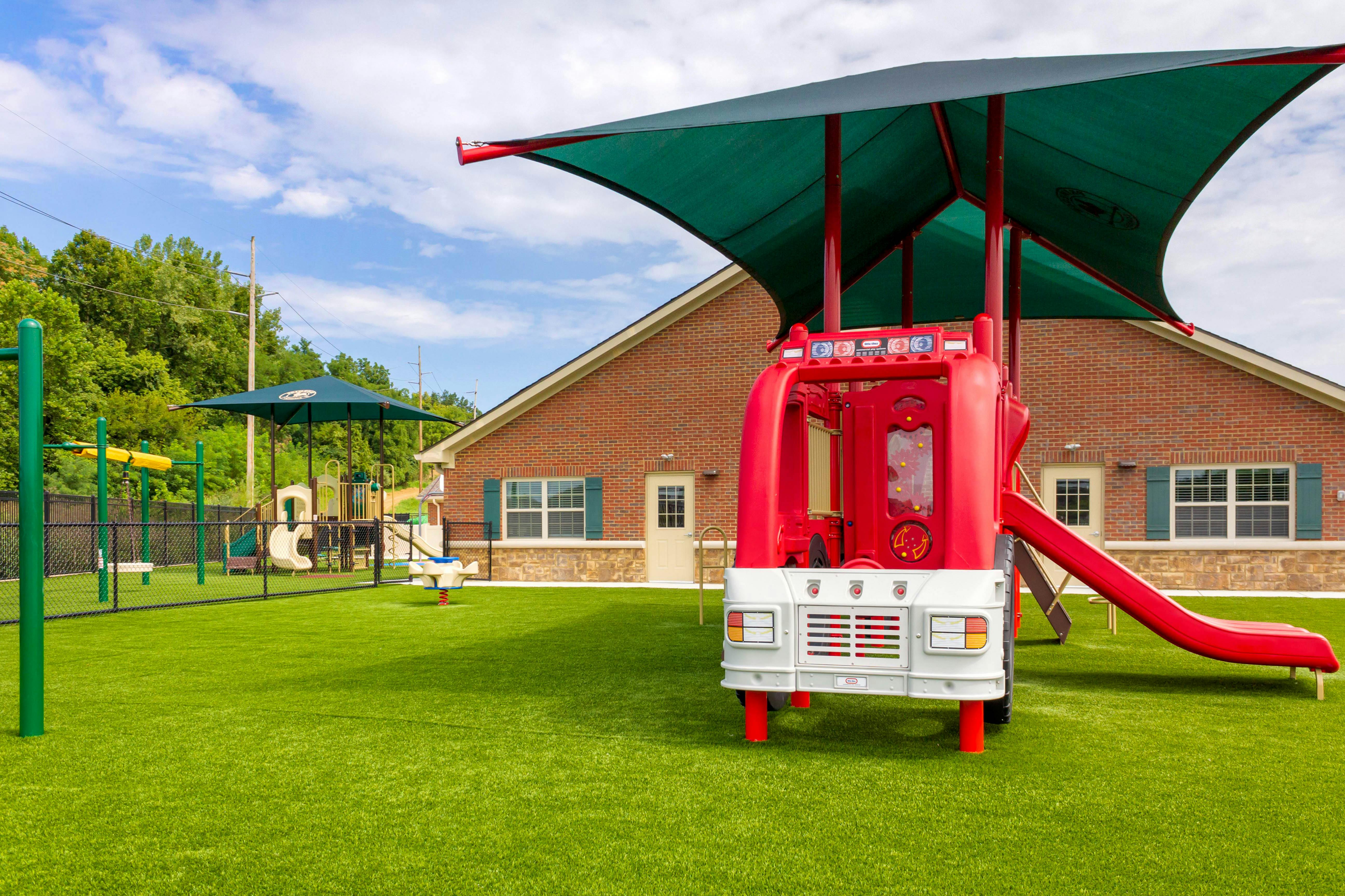 Red fire truck-shaped play structure with slide on artificial turf playground