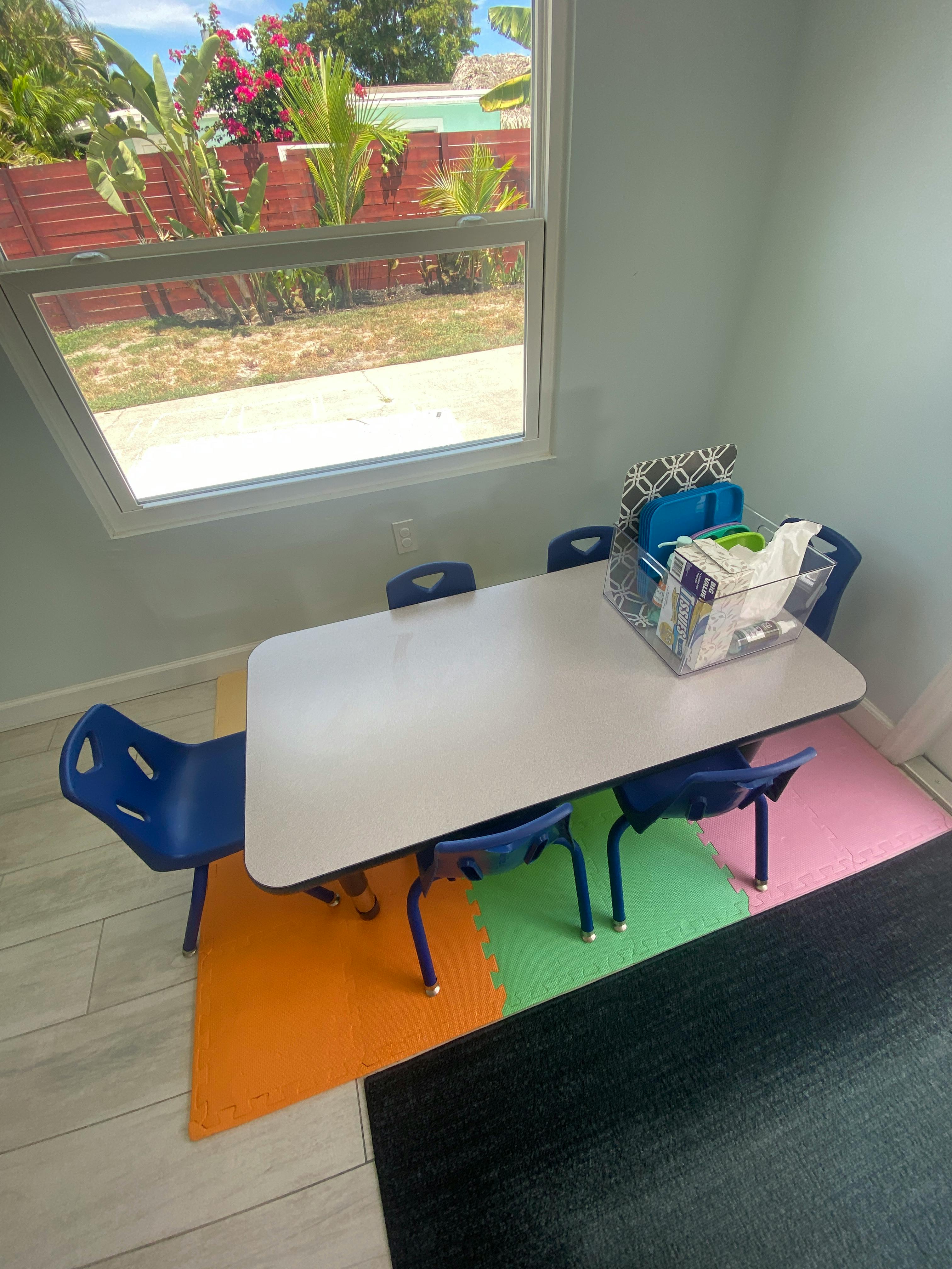 Small white table with blue chairs on colorful floor mats