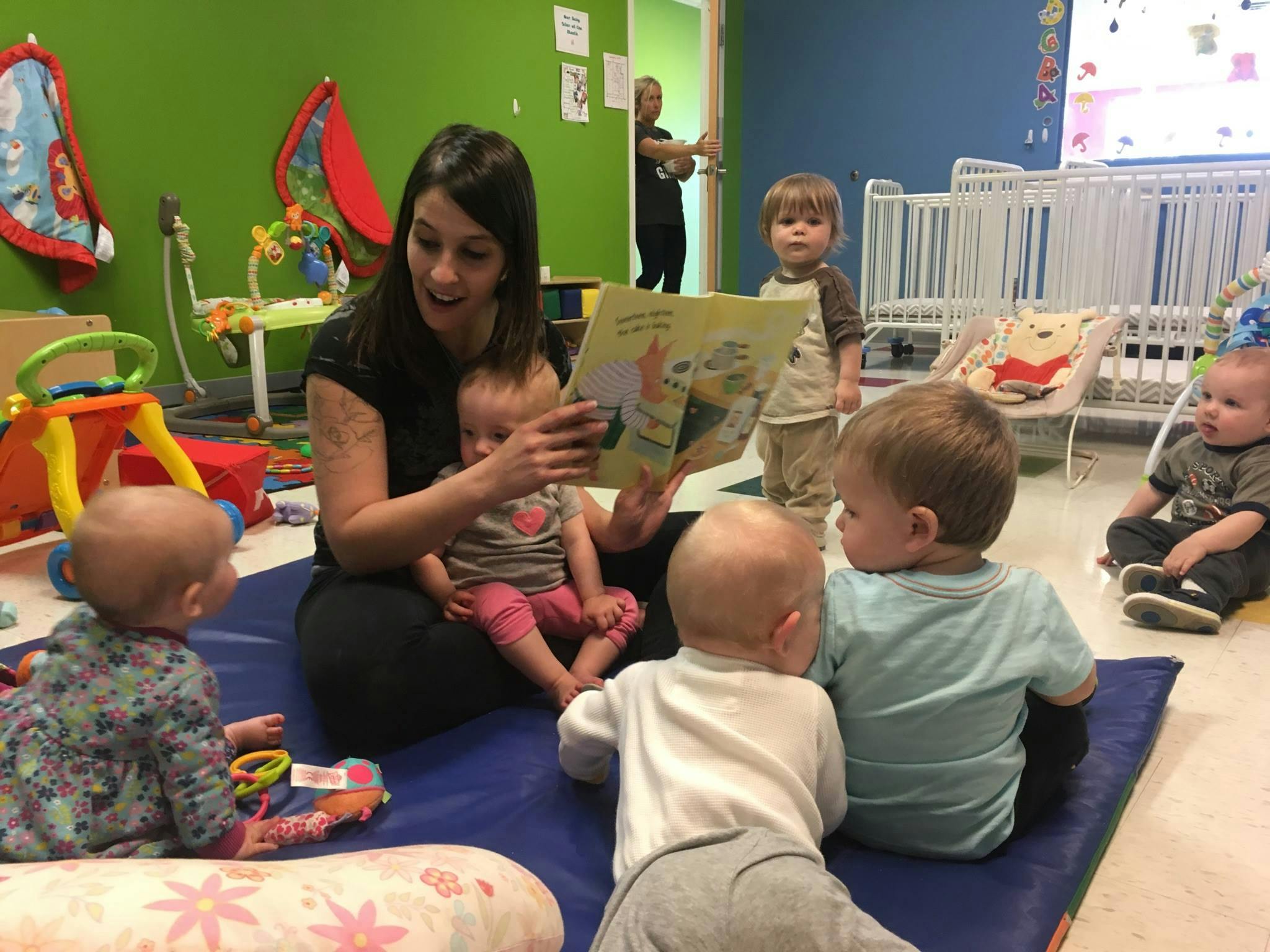 Person reading a book to a group of children in a classroom