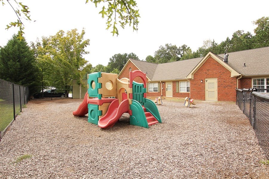 Playground with slides and climbing structure in front of a brick building