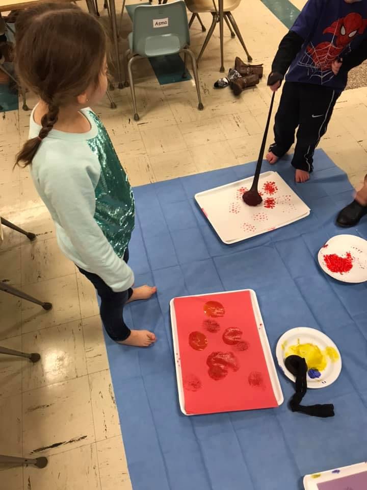 Two children painting on paper with sponges