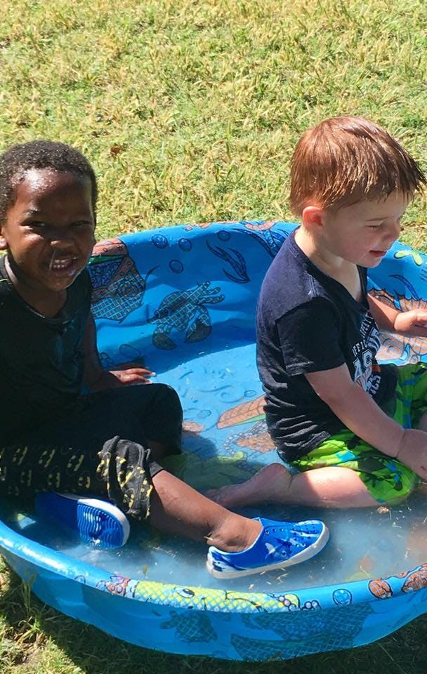 Two children sitting in a small blue wading pool