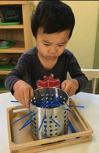 Child playing with blue sticks and a metal container