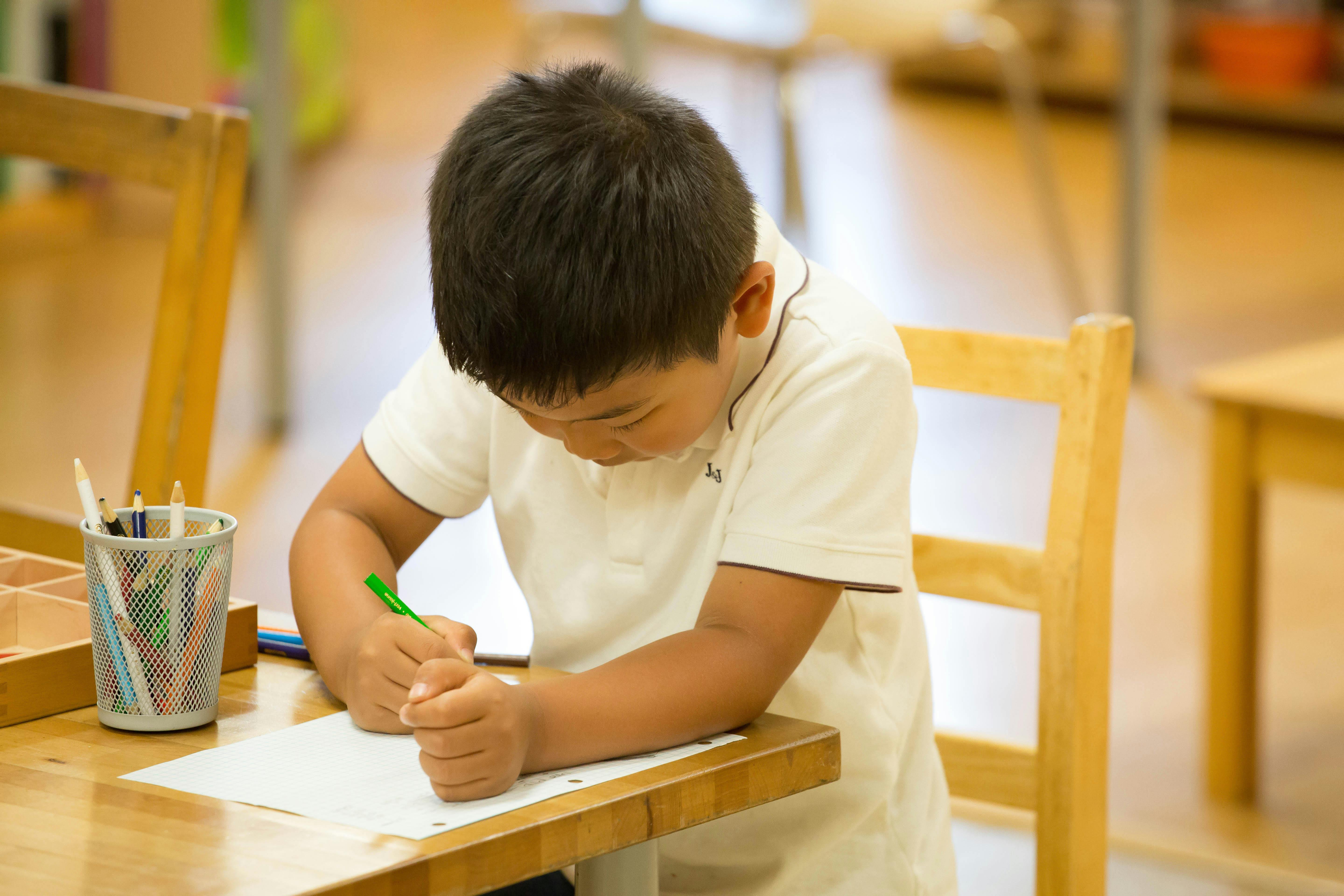 Child writing at a desk in a classroom
