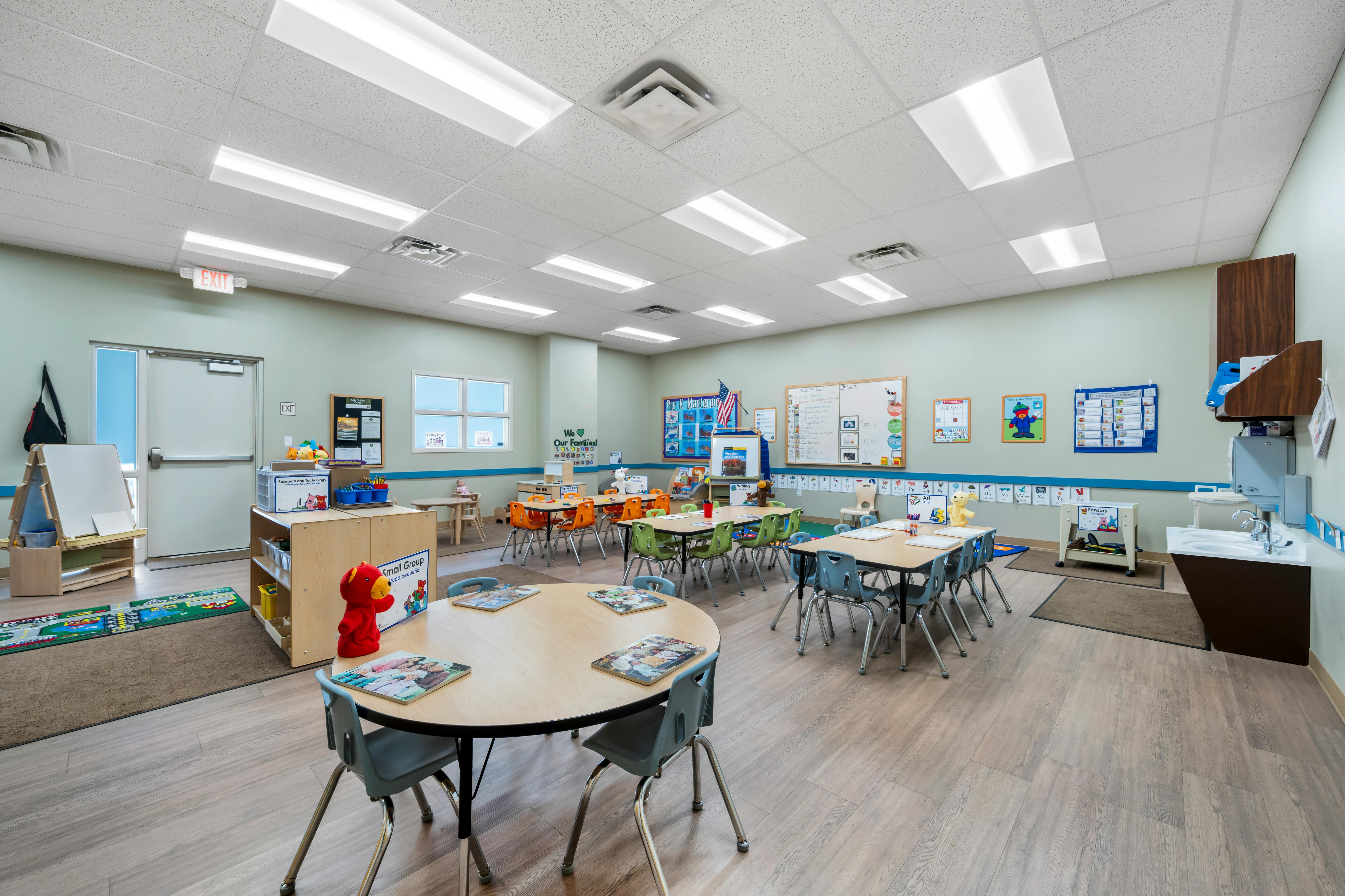 An empty early childhood classroom with multiple tables and chairs