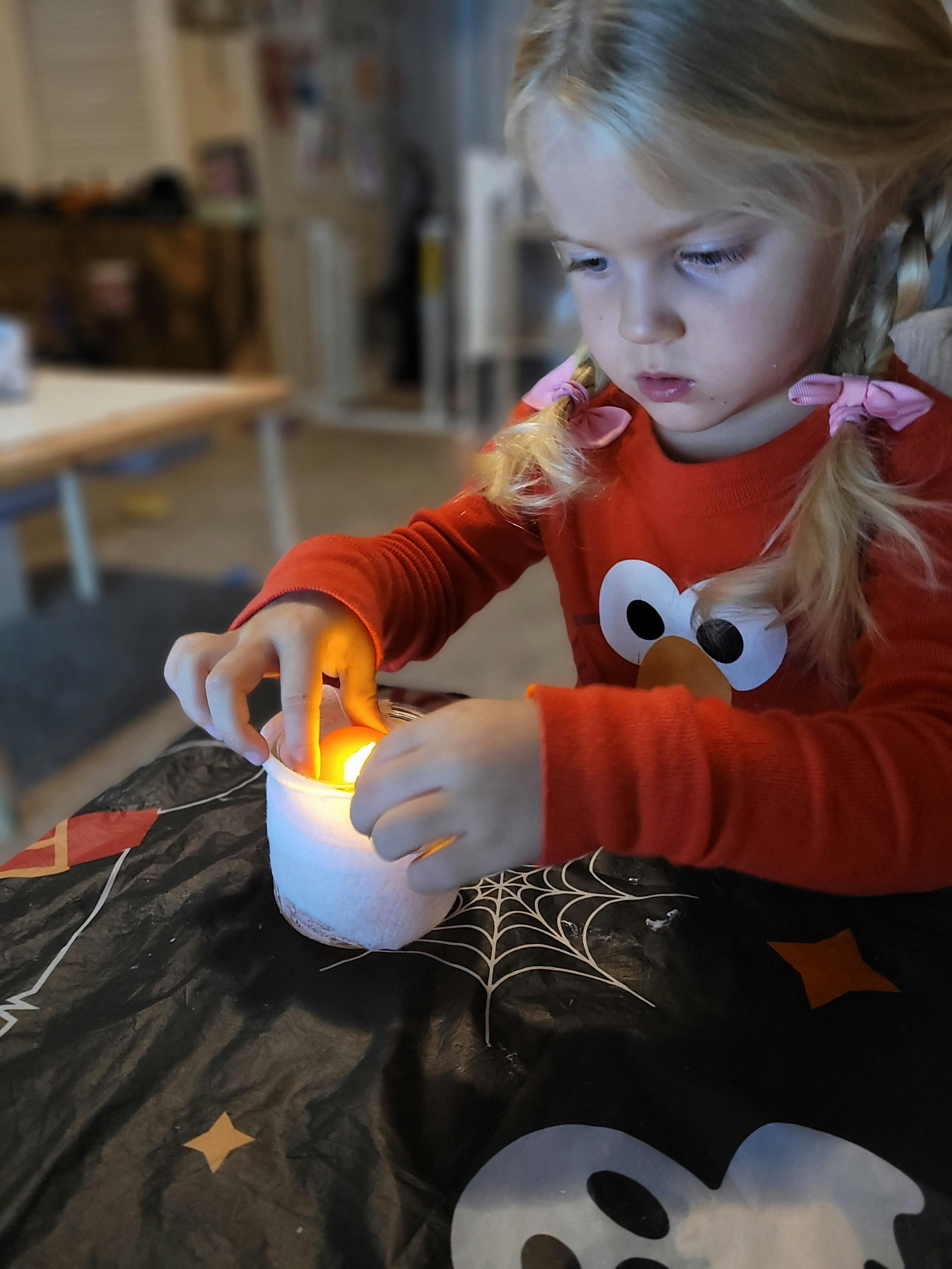Child in red shirt touching a glowing white object