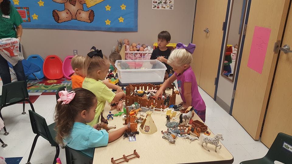 Children playing with toys at a table in a classroom