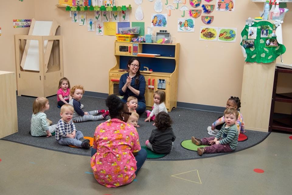 Adults and children sitting in a circle in a classroom