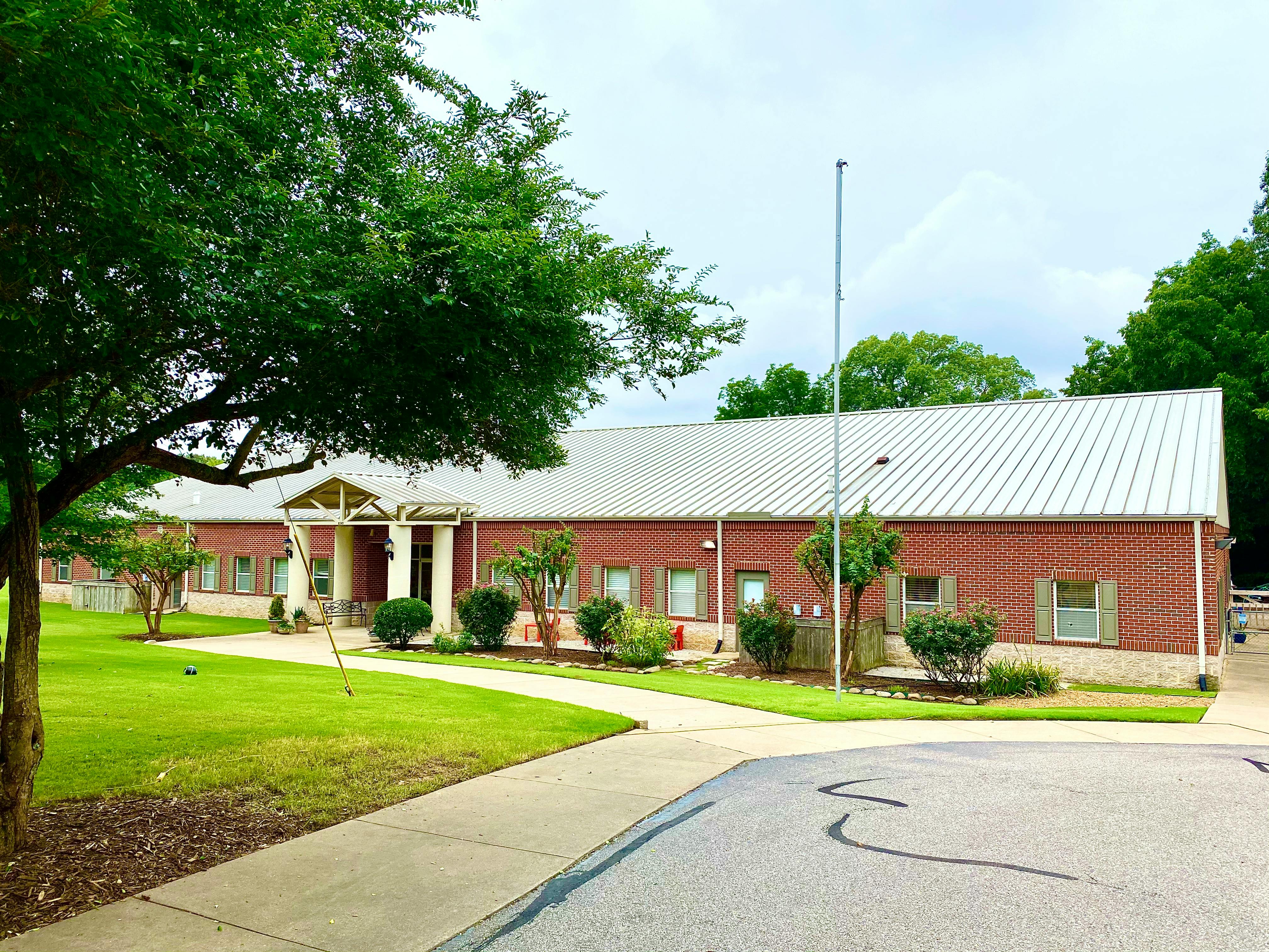 Brick building with a white roof and a flagpole in front