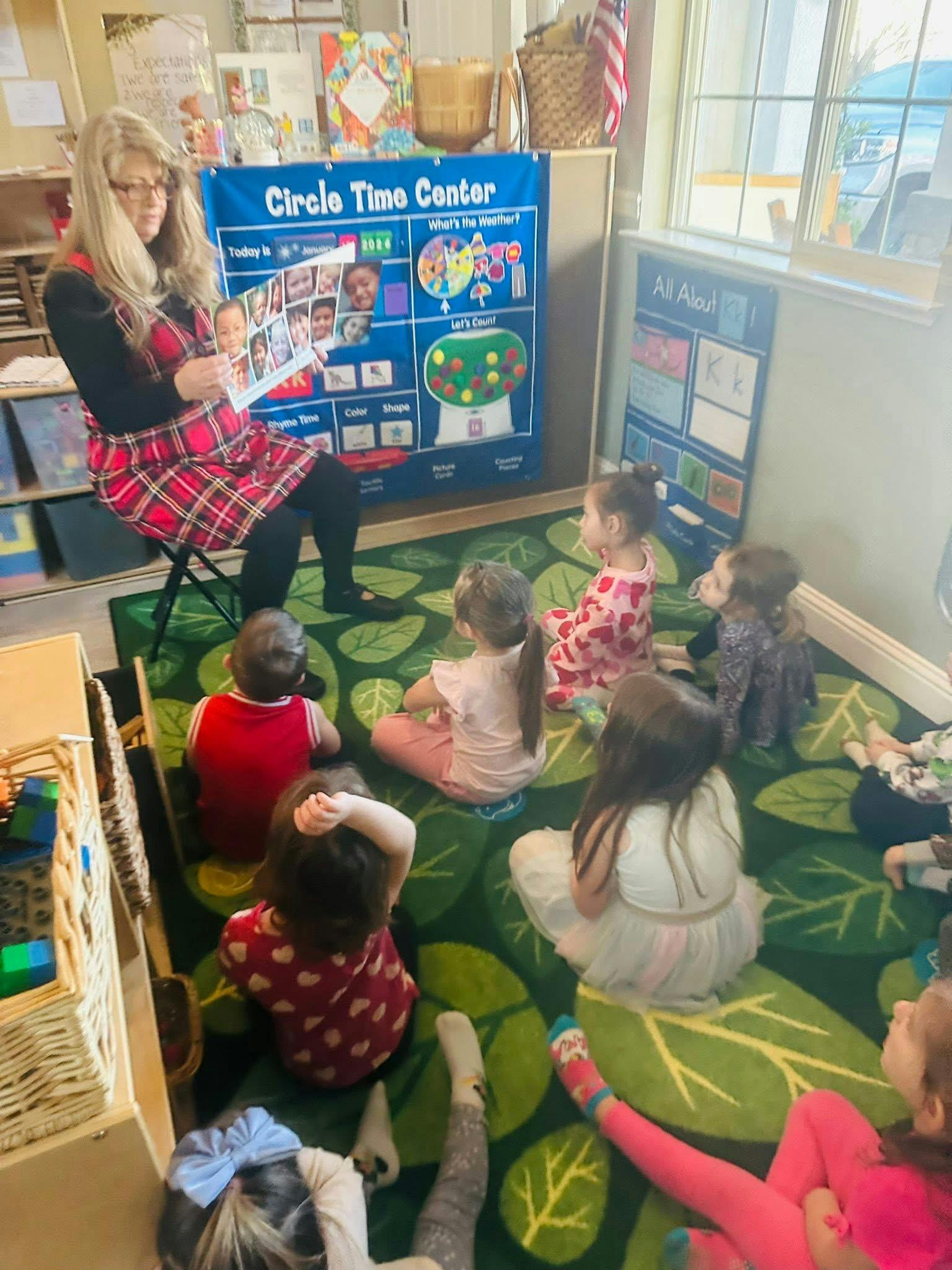 A person reads a picture book to a group of children in a classroom