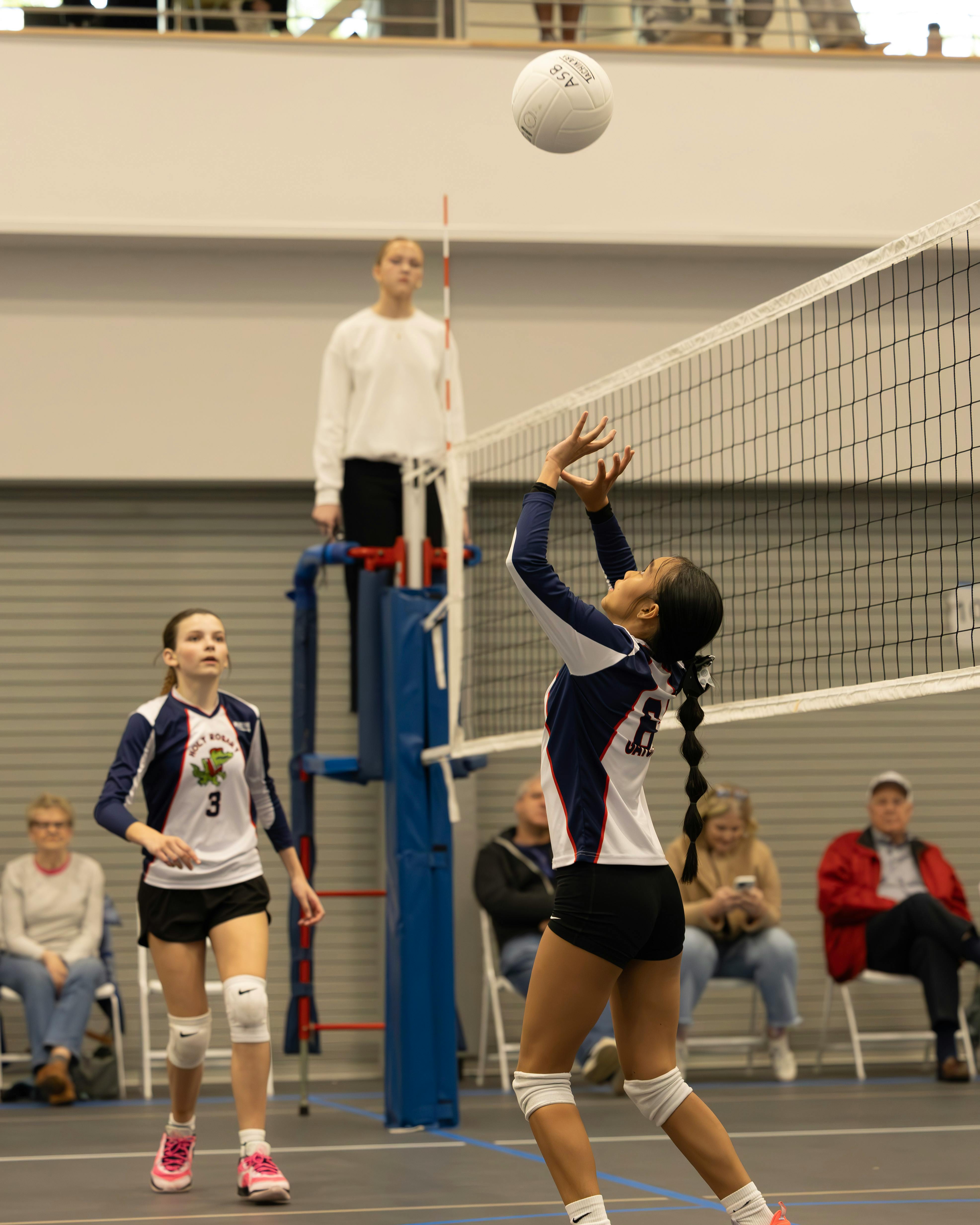 Person setting a volleyball over the net during a game