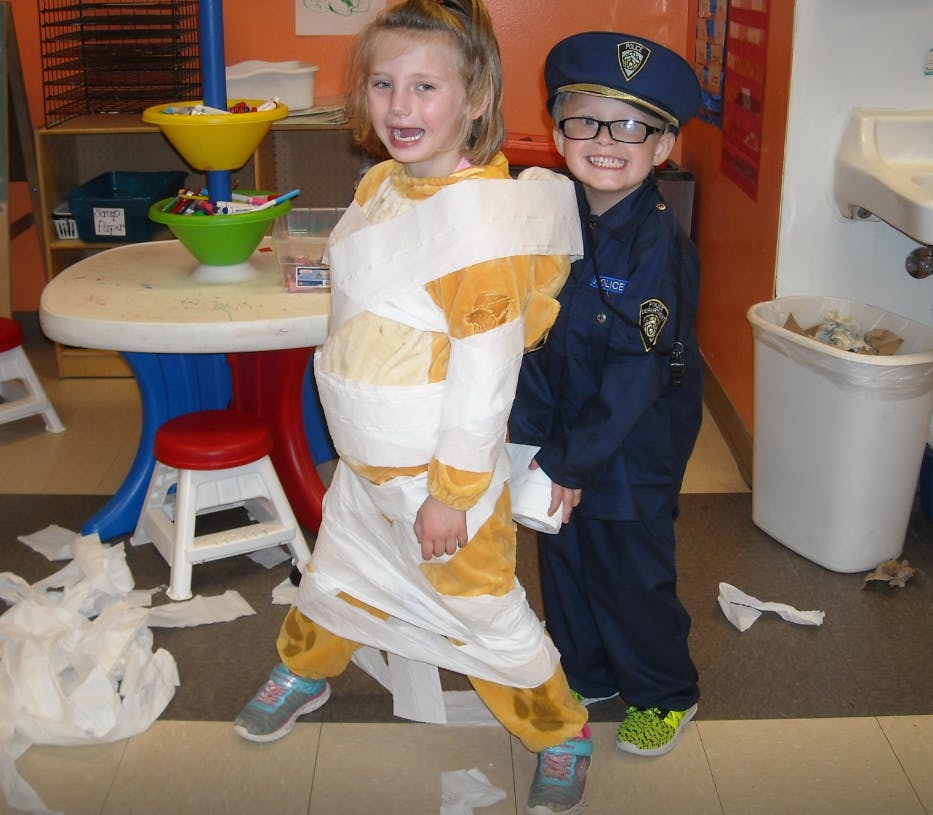Child in mummy costume and child in police costume standing together