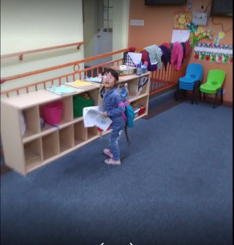 Child standing in a classroom holding paper