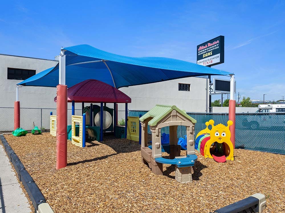 Playground with several pieces of play equipment under a blue shade covering