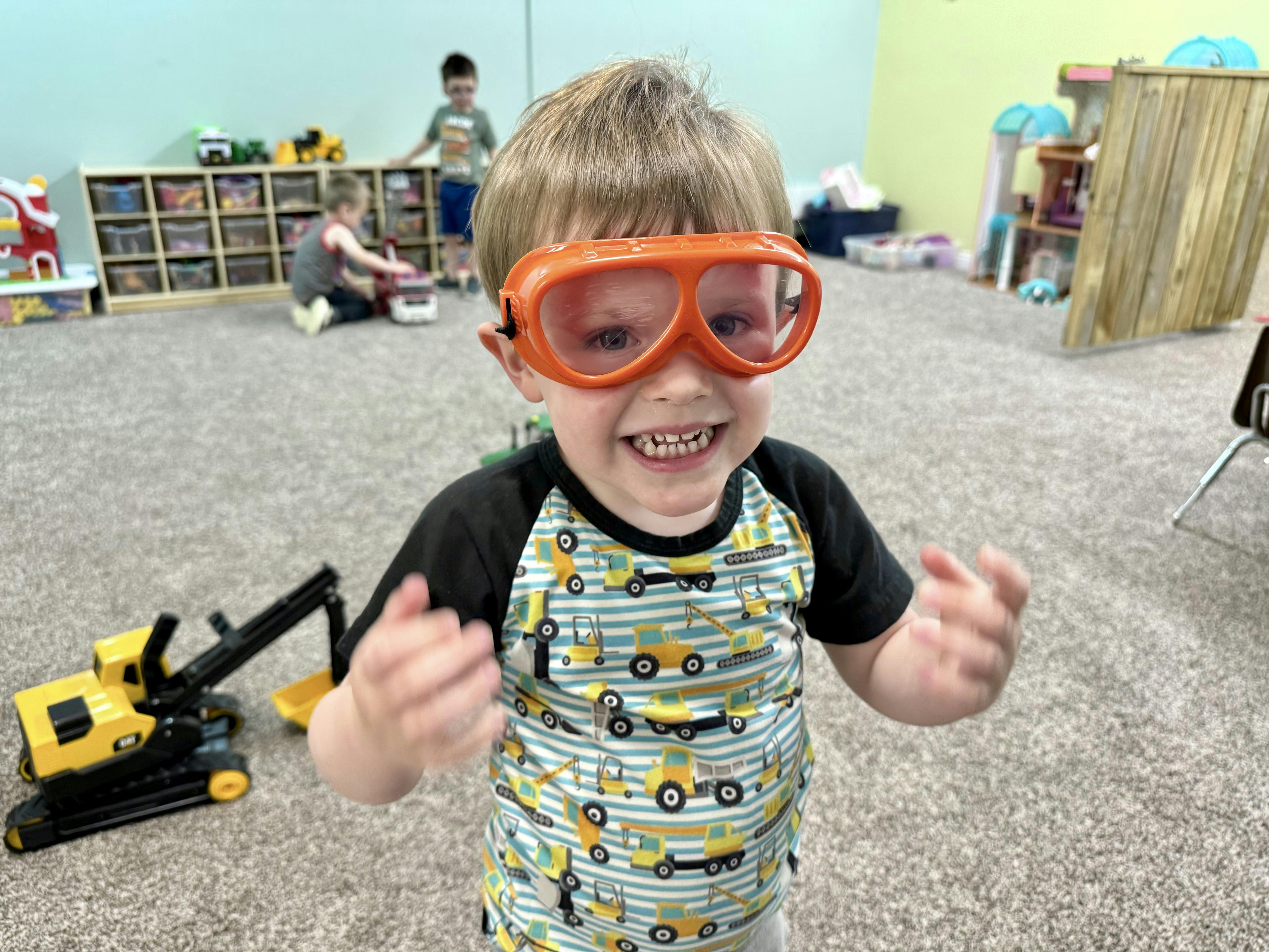 Child wearing orange goggles in a playroom