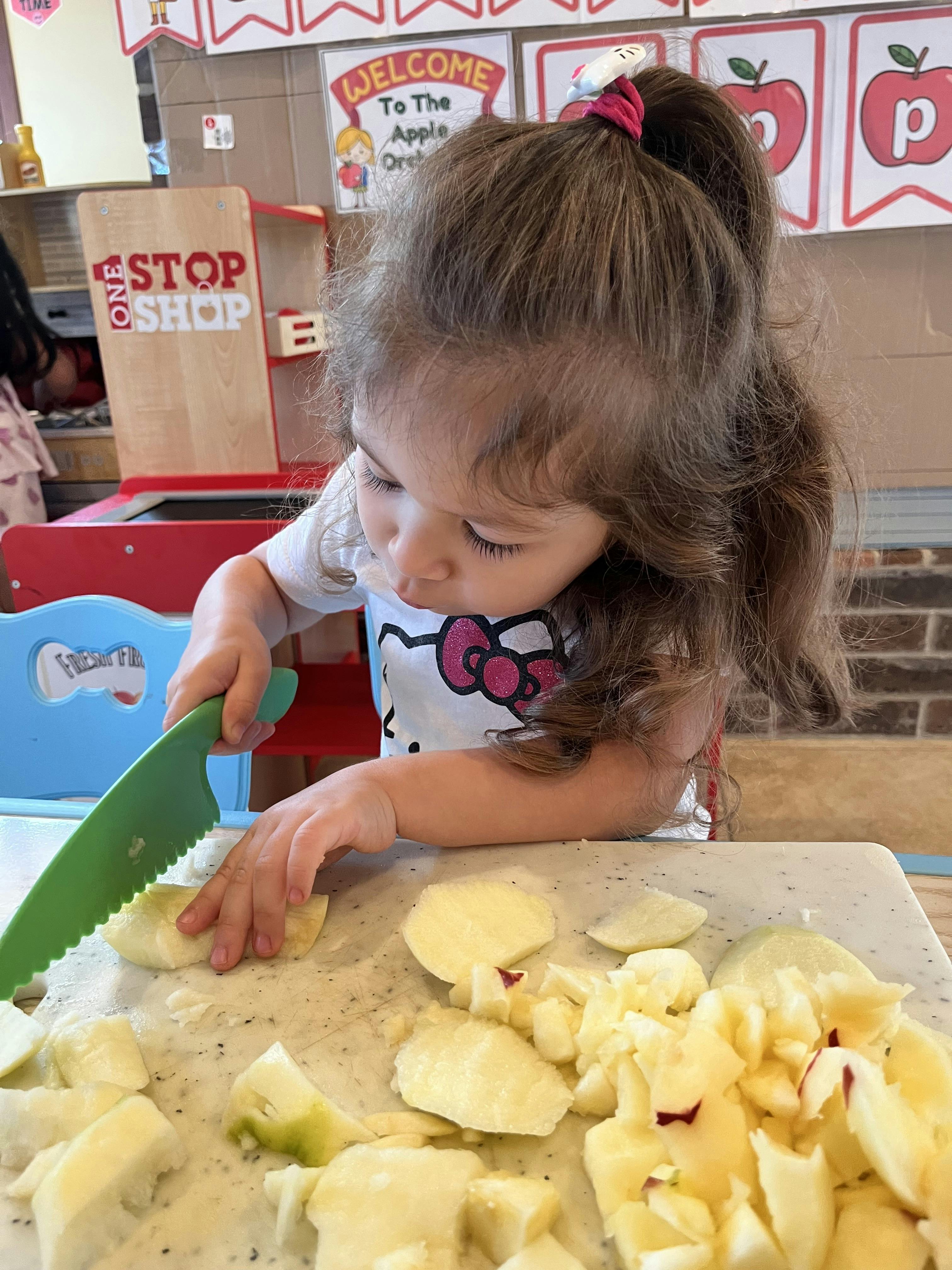 Child cutting apples with a plastic knife