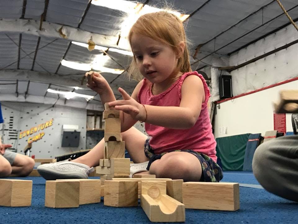 Child playing with wooden blocks on a blue mat