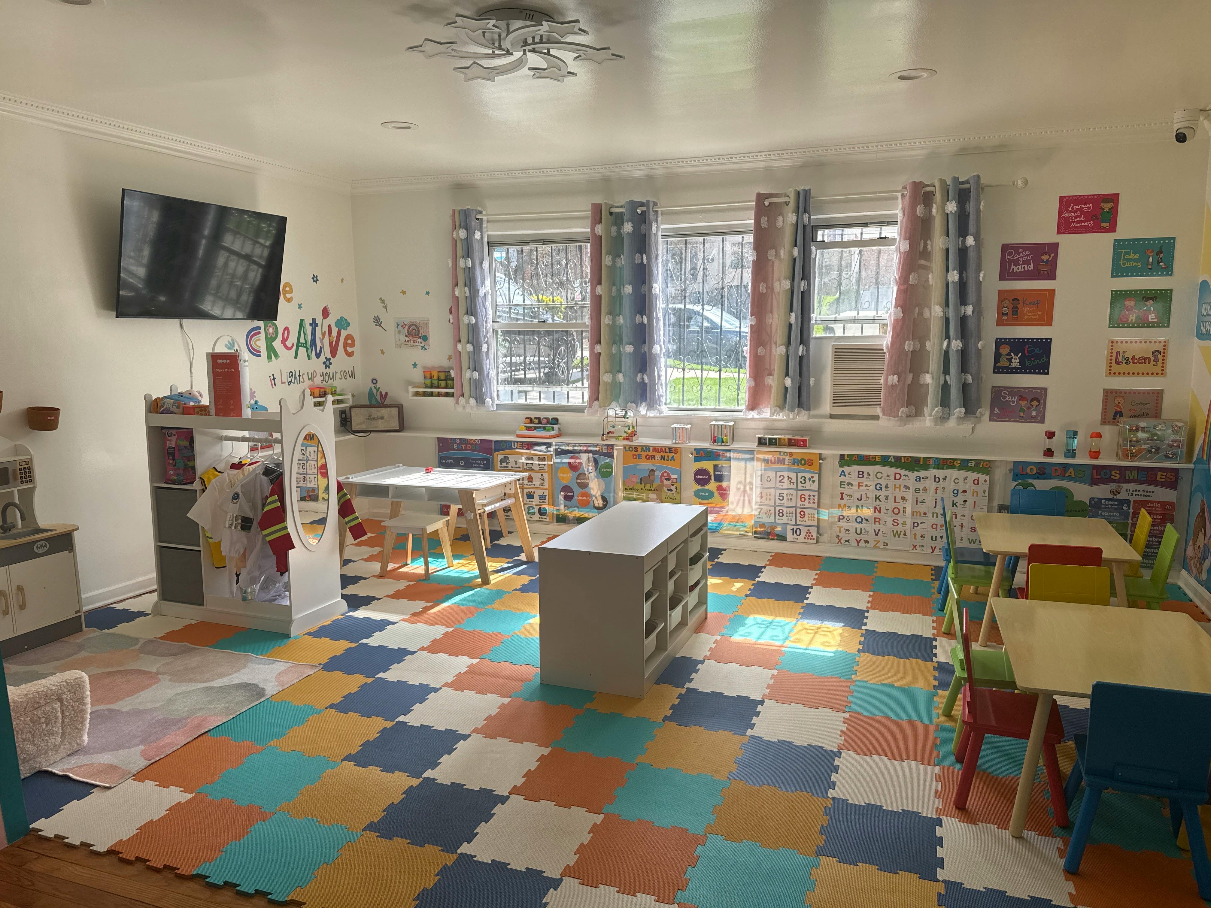 Classroom with colorful floor tiles, small tables and chairs, and a TV on the wall