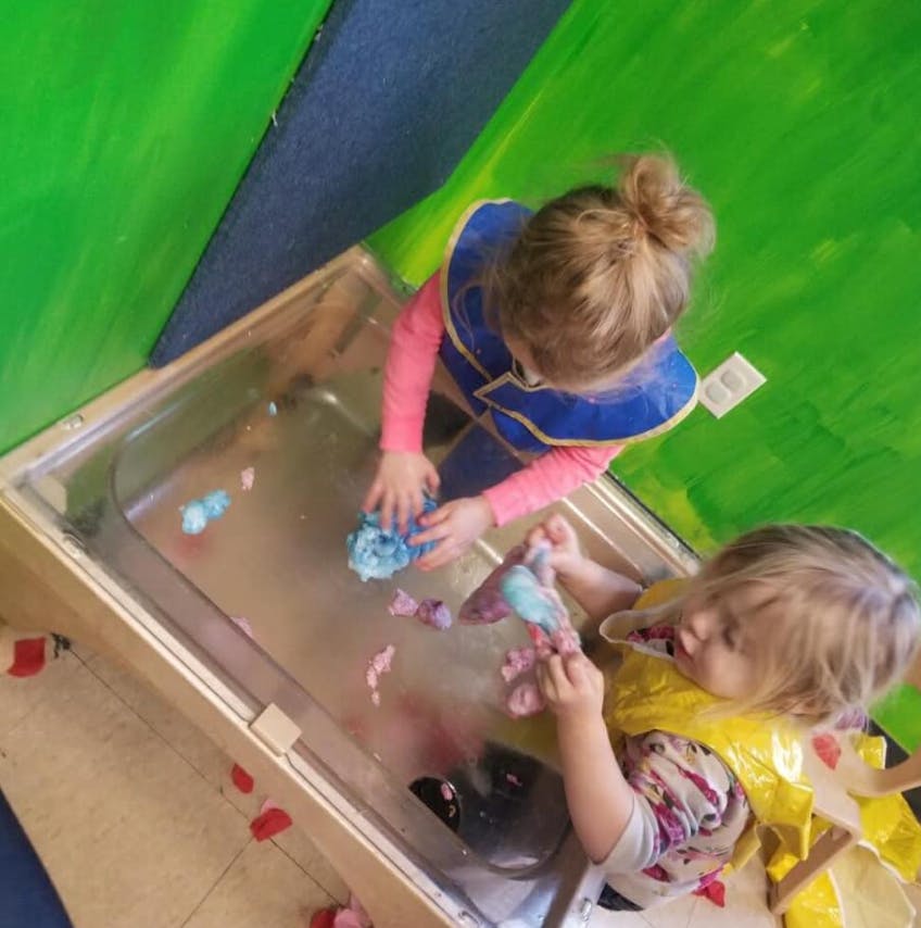 Two children playing with toys in a water table
