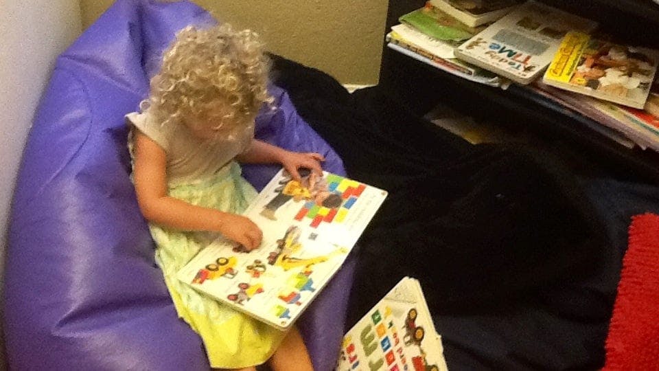 Child sitting in a beanbag chair and looking at a book