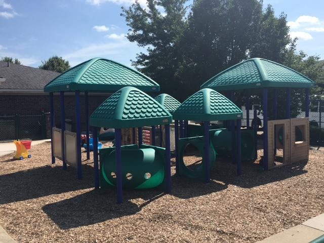 Empty children's playground with green and blue equipment on wood chips