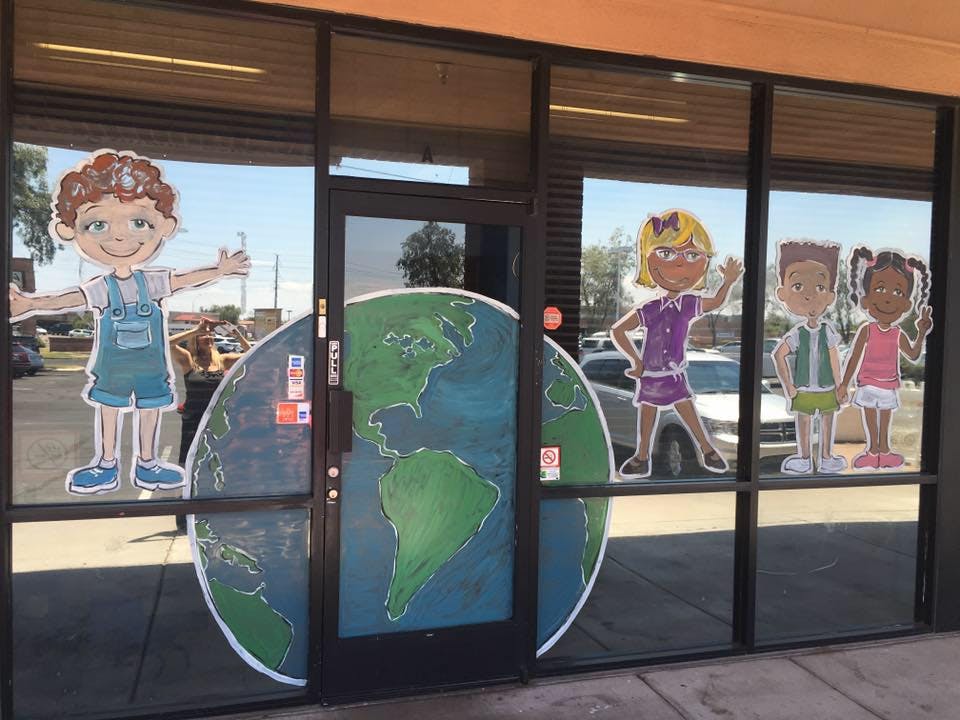 Window decorated with cartoon children and a large globe