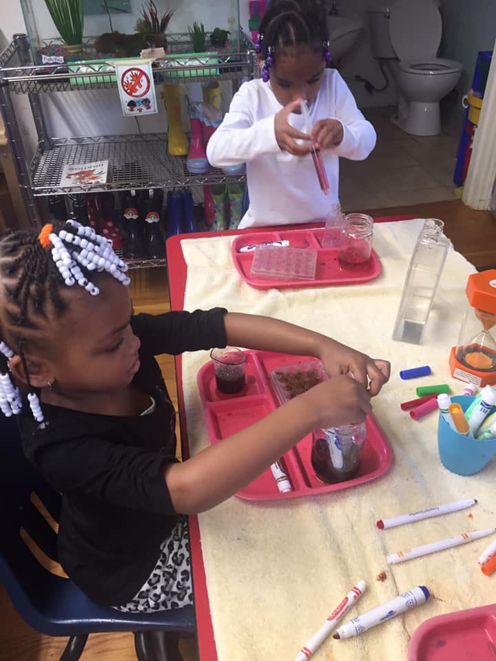 Two children at a table with trays and craft supplies