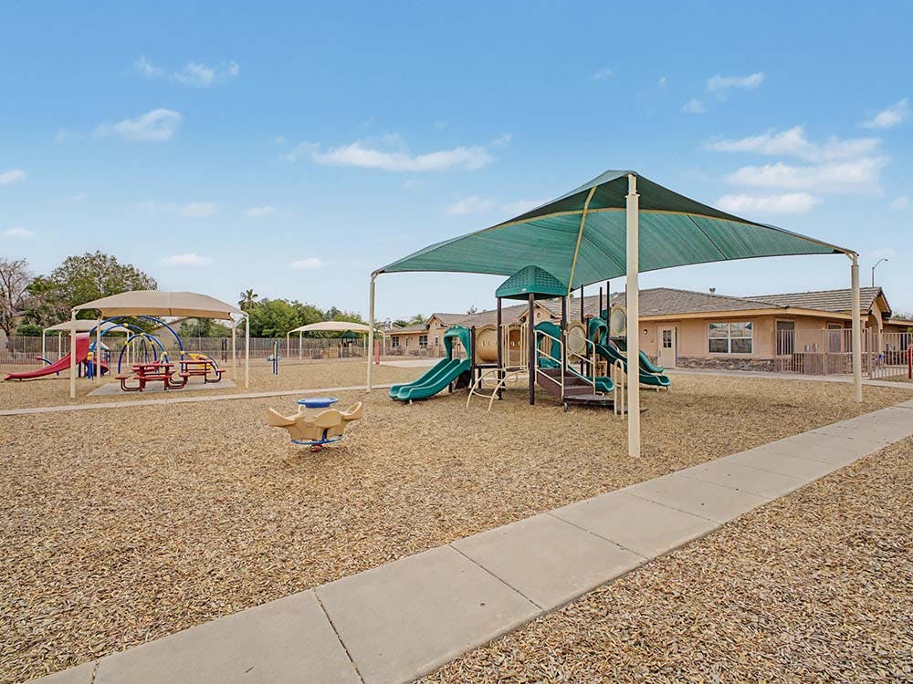 Playground with swings, slides, picnic tables, and shade structures
