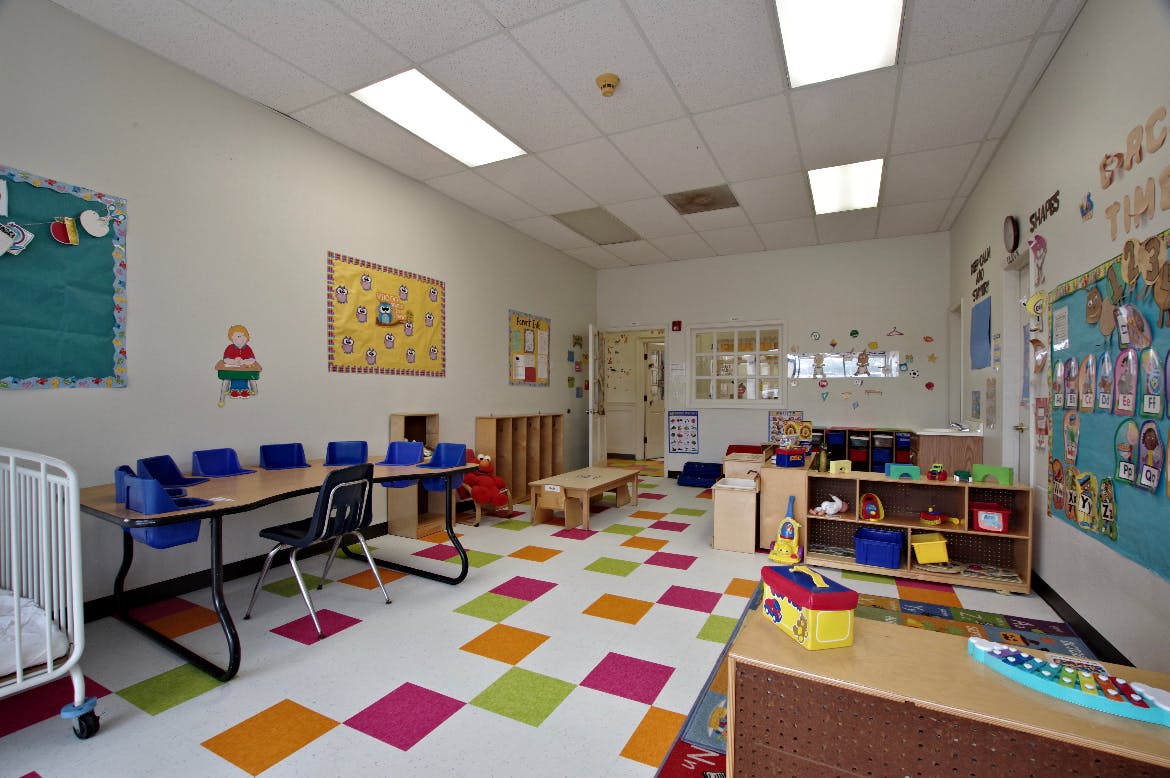 Empty classroom with colorful floor tiles and child-sized furniture