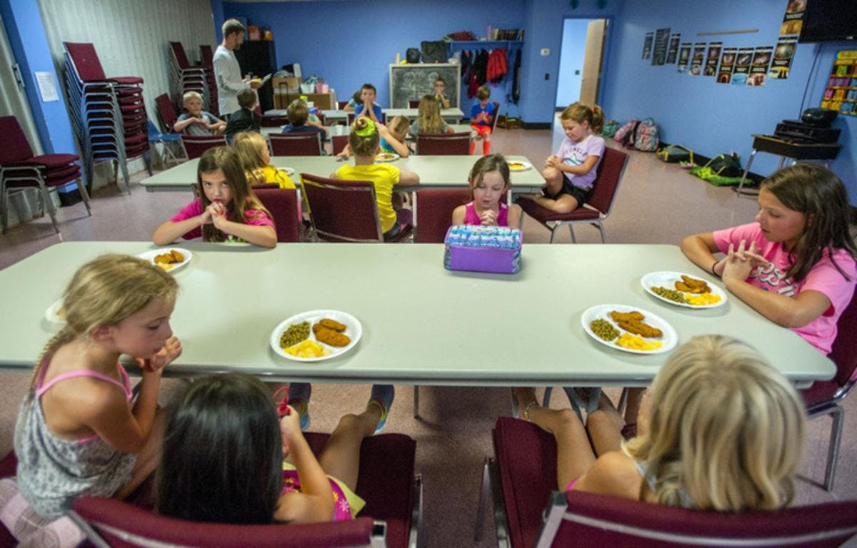 Children sitting at tables with plates of food