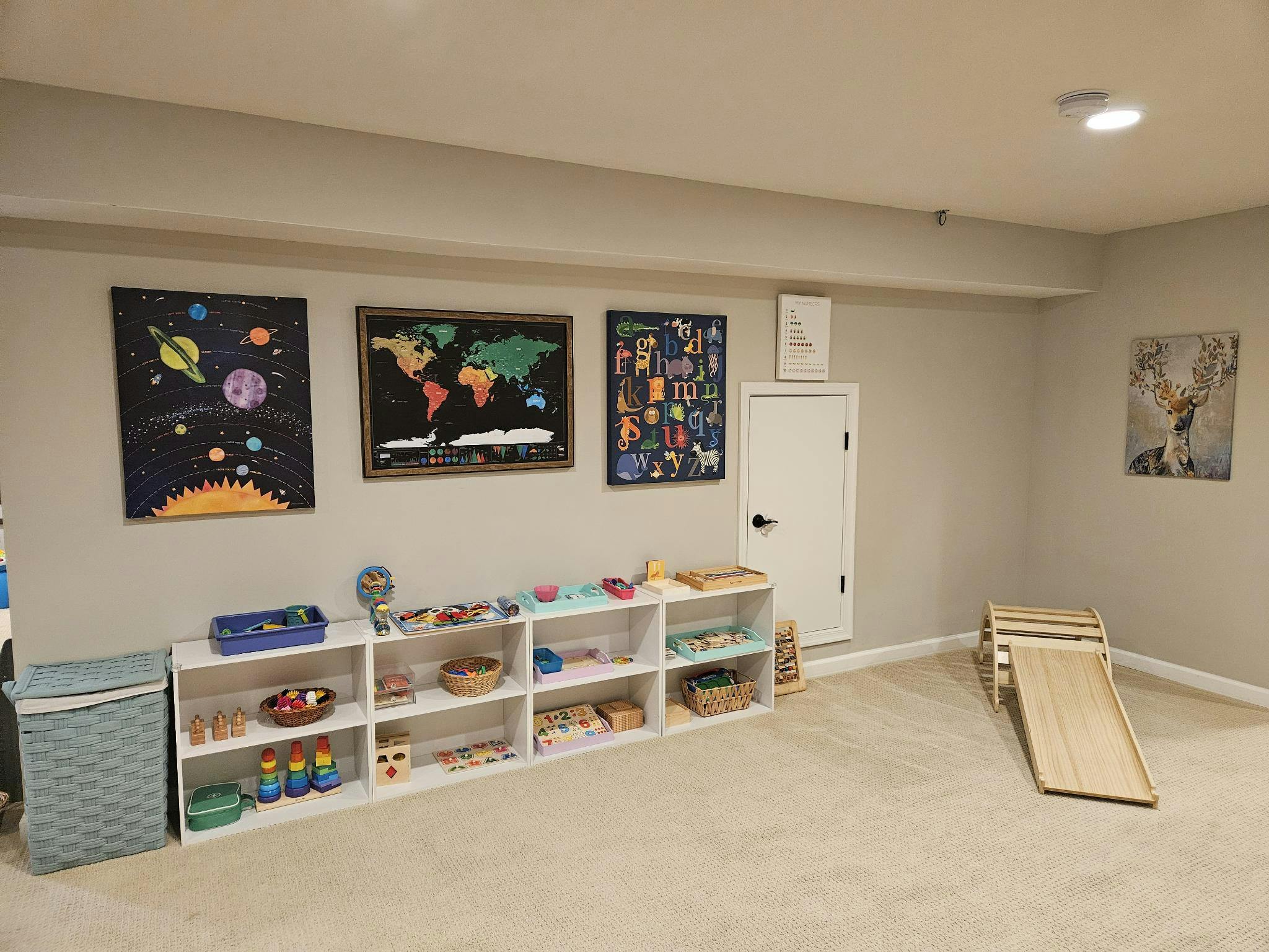Playroom with wall art, shelves of toys, and a wooden climbing structure