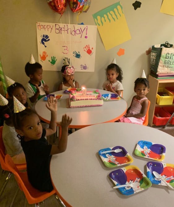 Children in party hats around tables with a birthday cake