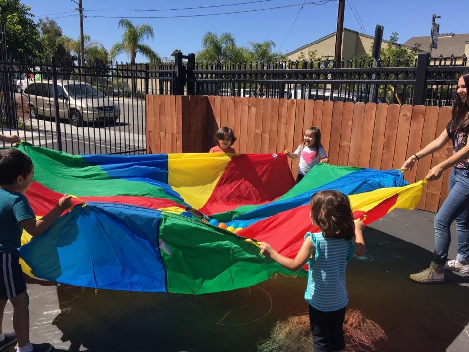 Children and an adult playing with a colorful parachute