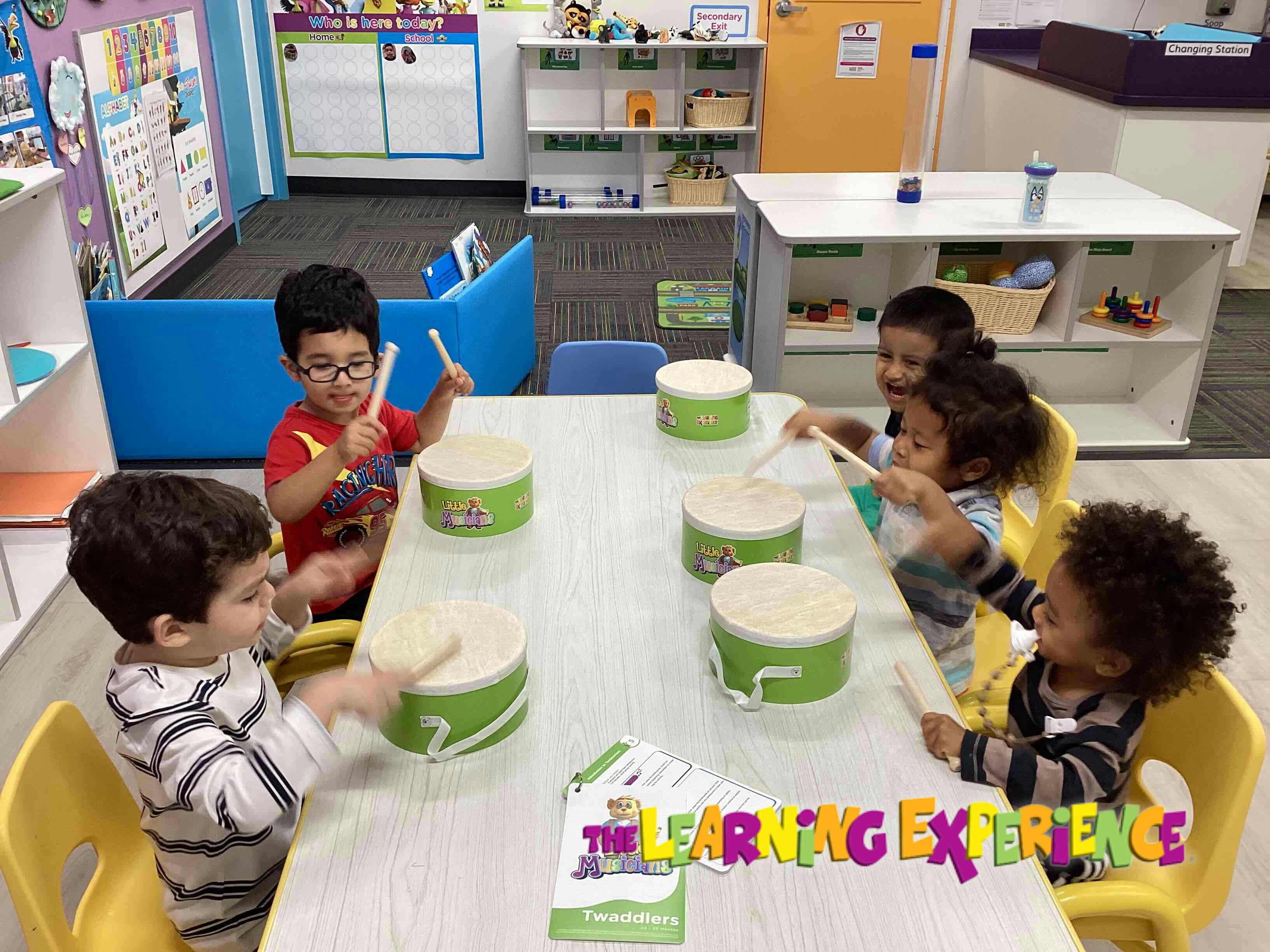Children playing drums at a table