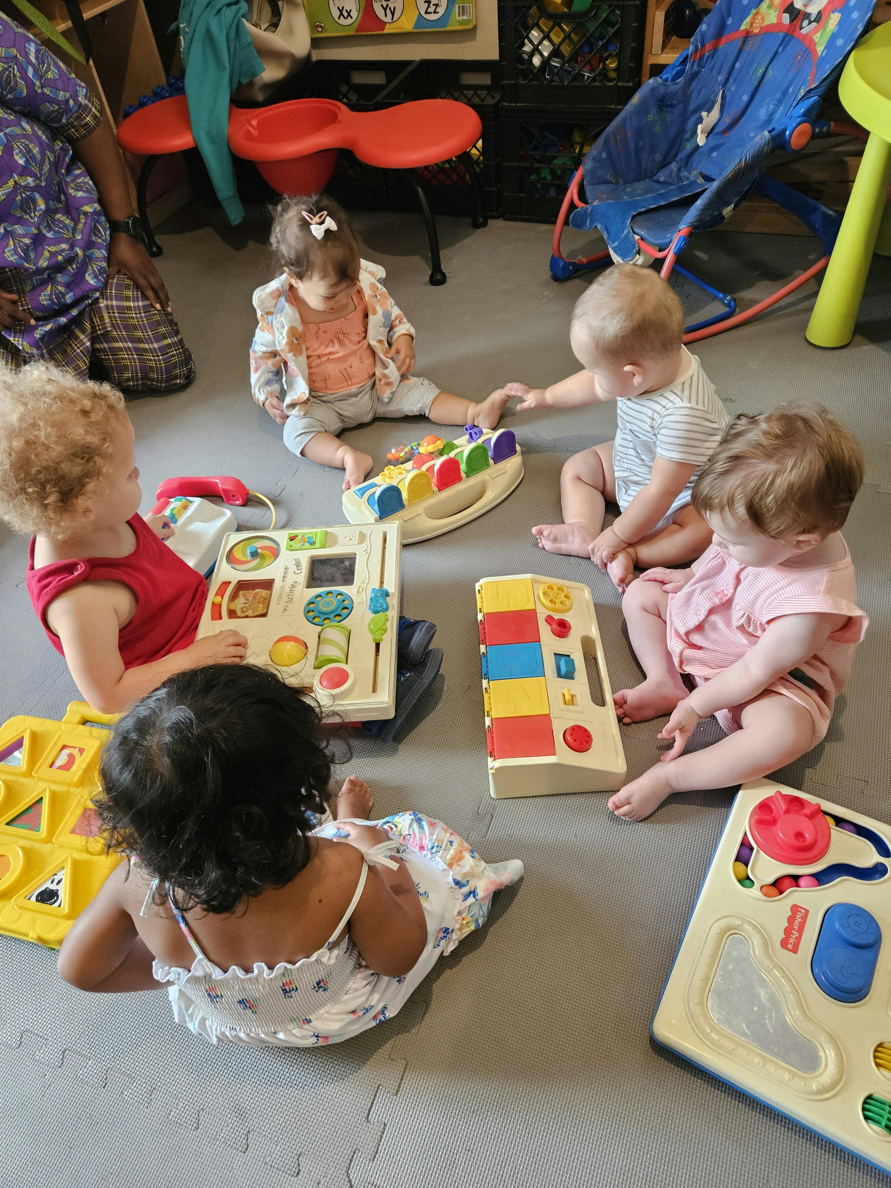 Multiple children playing with toys on the floor in a classroom