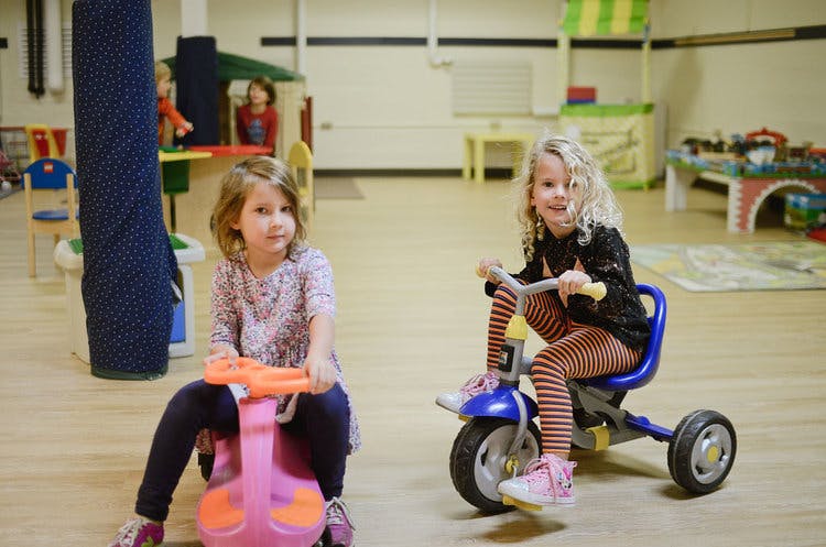 Two children riding toy vehicles indoors